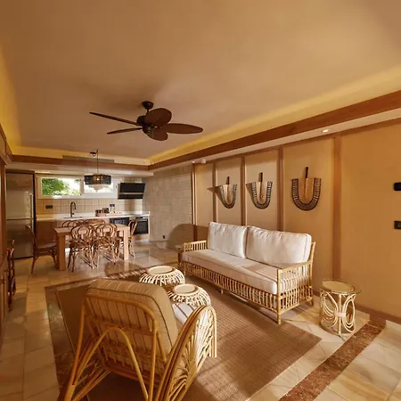 Bahia Principe Luxury Cayo Levantado - All Inclusive Samaná Habitación foto The photo shows a bright and airy living area of a vacation home or resort, featuring a blend of rustic and comfortable elements. The walls are a warm, light beige, accented by wooden trim along the ceiling and around doorways. 

The main living spac